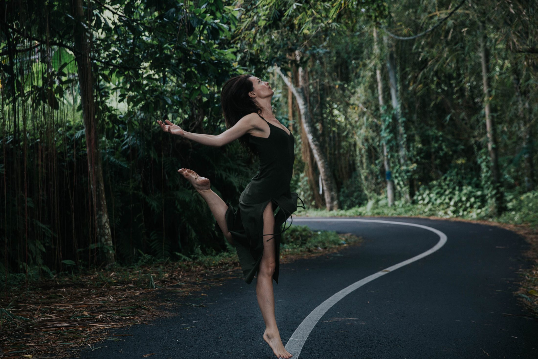 Robyn leaping joyfully, arms open, on a jungle road in Bali